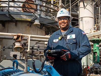 Operator with clipboard standing near a refinery unit