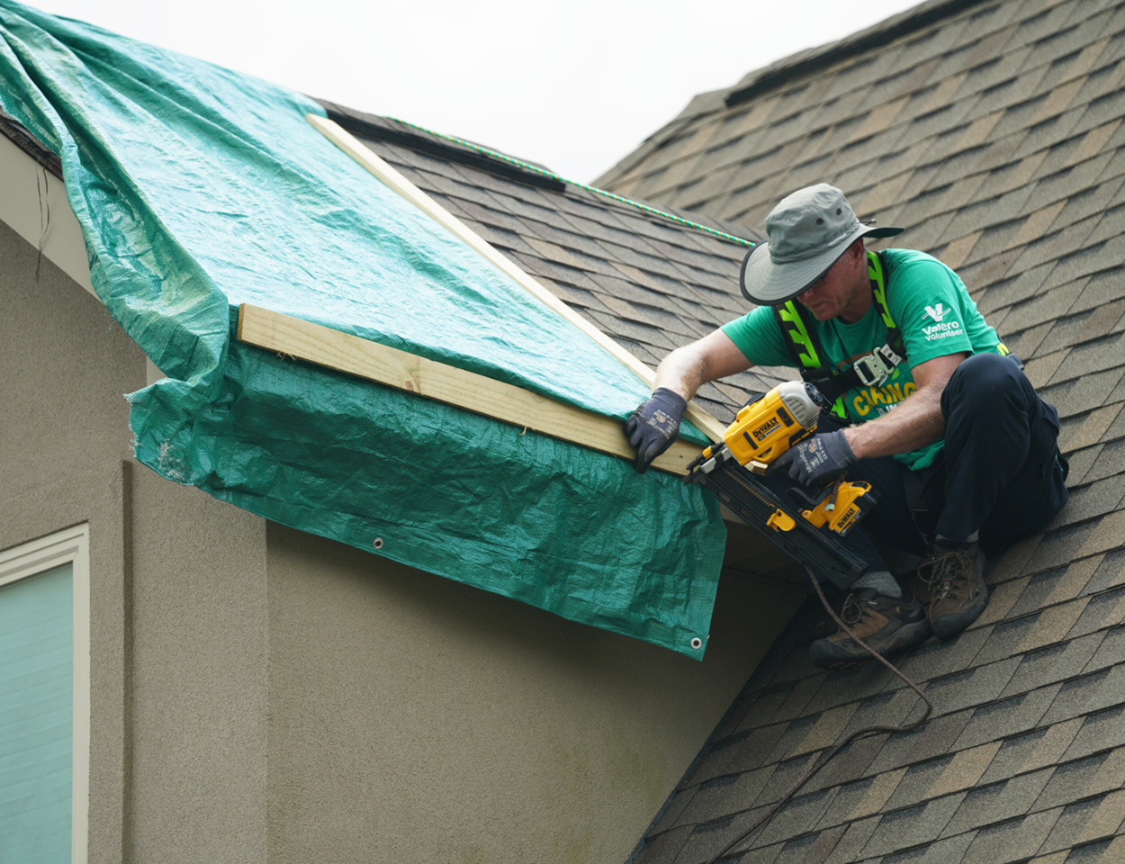 yd7610 volunteer on top of a home's roof fixing damages