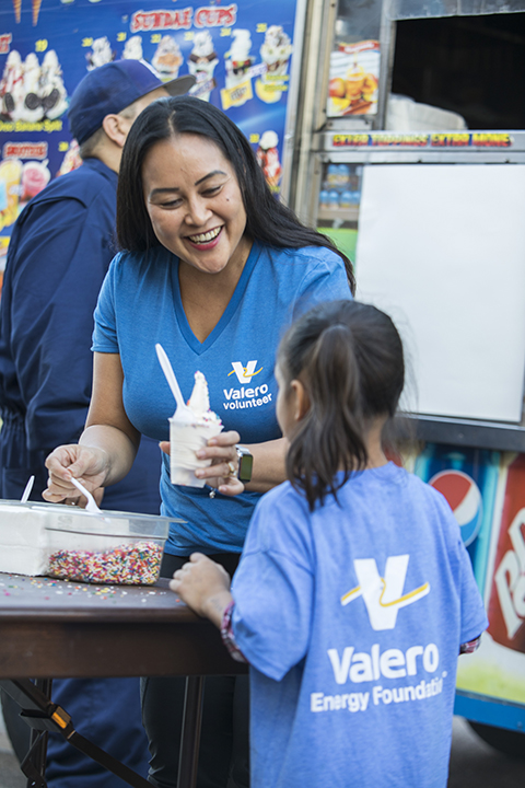 yd7610 Volunteer handing ice cream to young girl