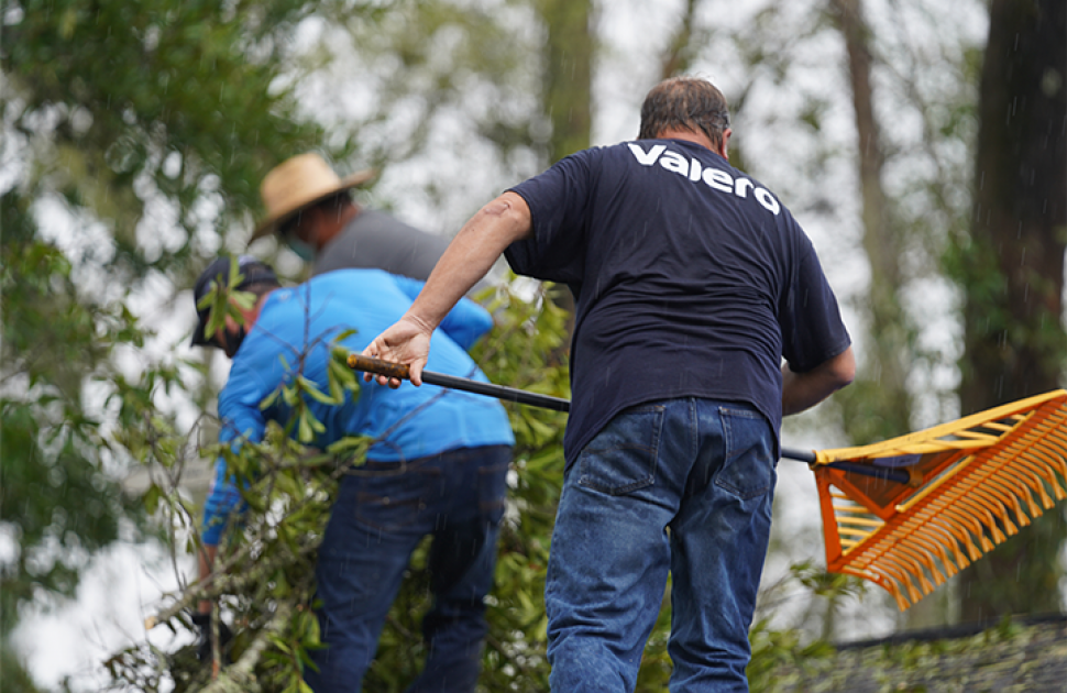 Volunteers clear debris off a house affected by a hurricane.