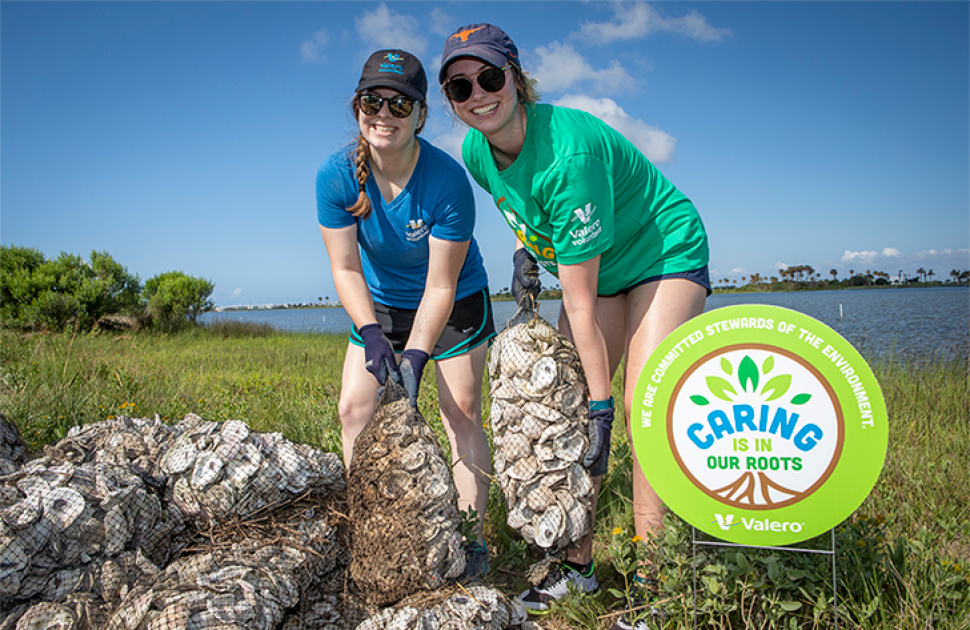 Two volunteers hold bags of oysters as part of a restoration project.