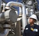 Operator walking near large-scale refining units and looking up at them