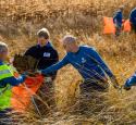 Volunteers put debris in a trash bag